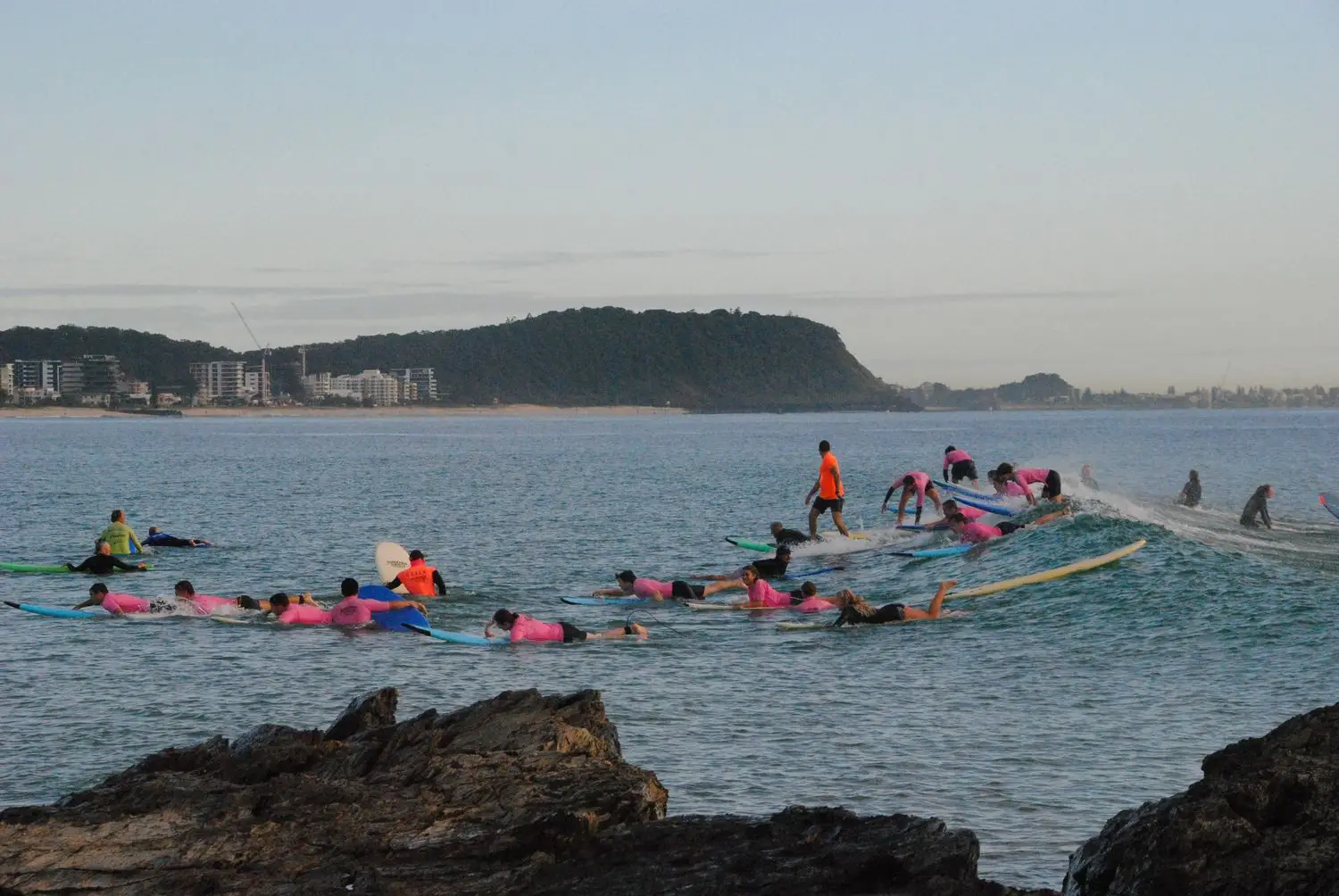 Group of surfers paddling together near the coast