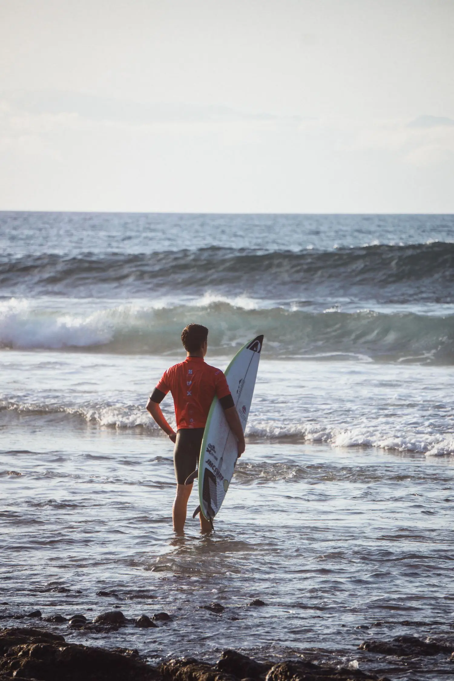 Surfer standing in shallow water with a surfboard