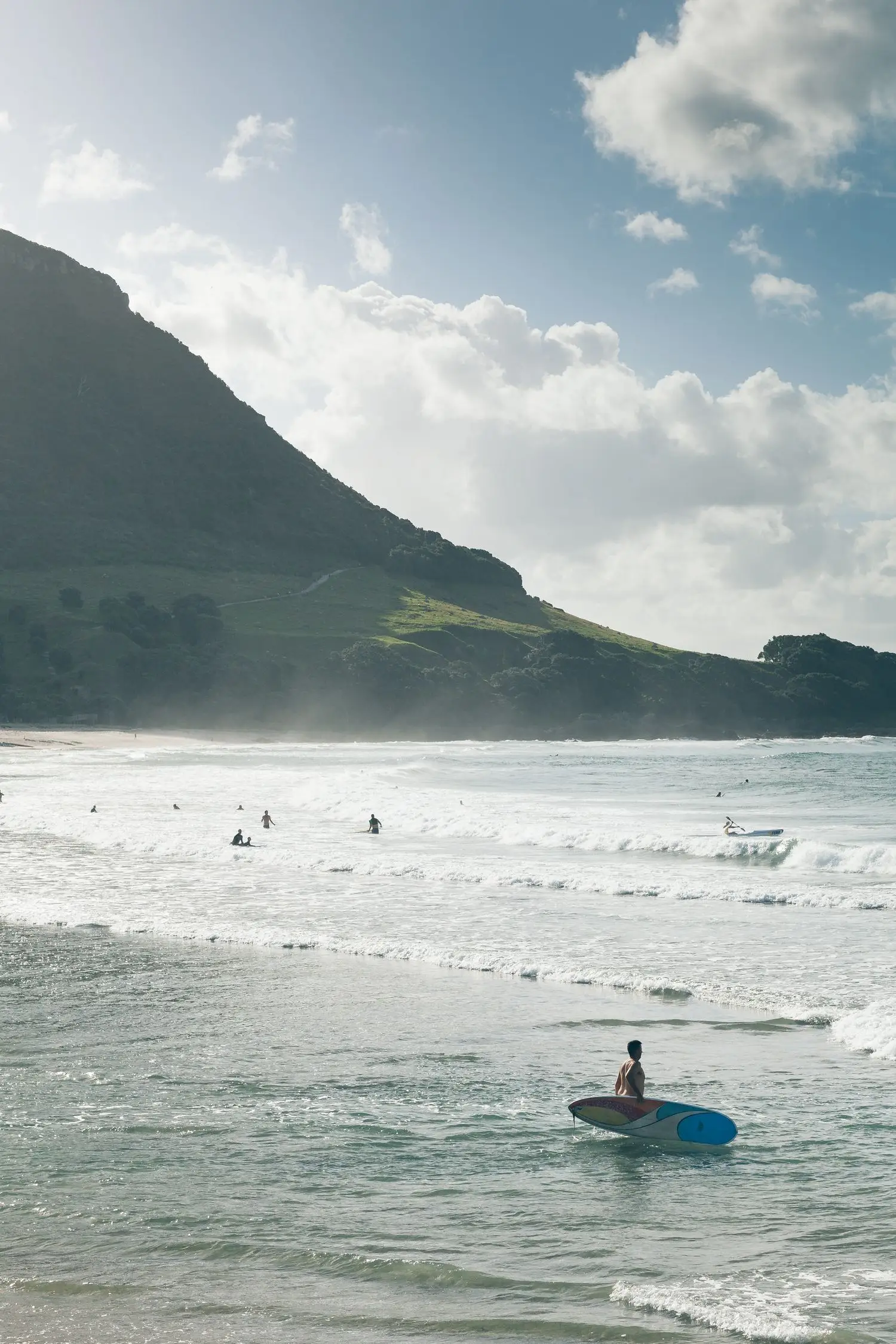 Surfers near a steep coastal headland and open water